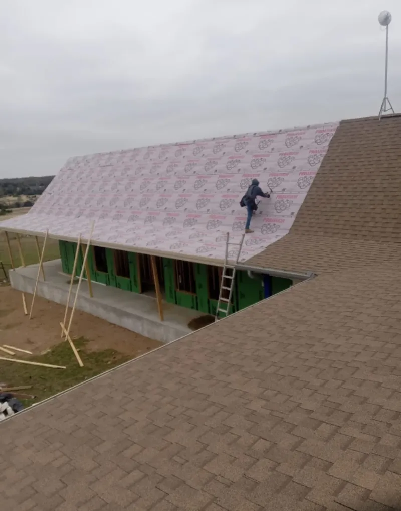 Worker preparing underlayment for a metal roof installation in Hot Springs